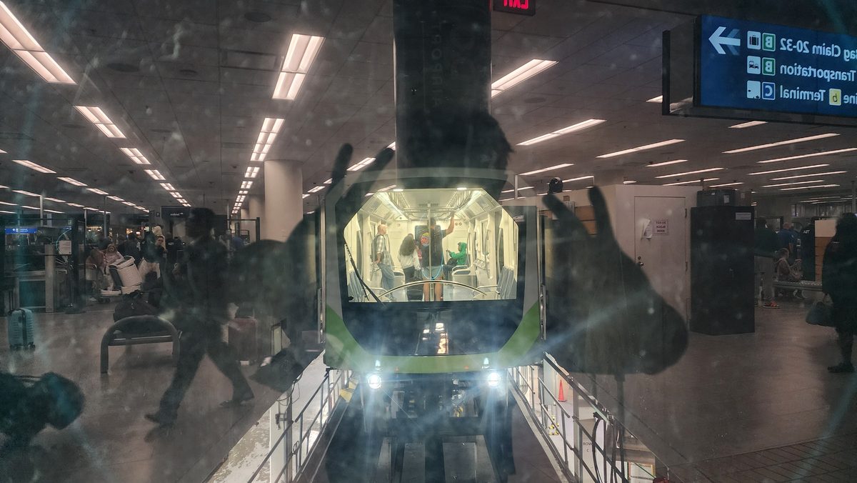 An airport people-mover train arriving at an early-morning station