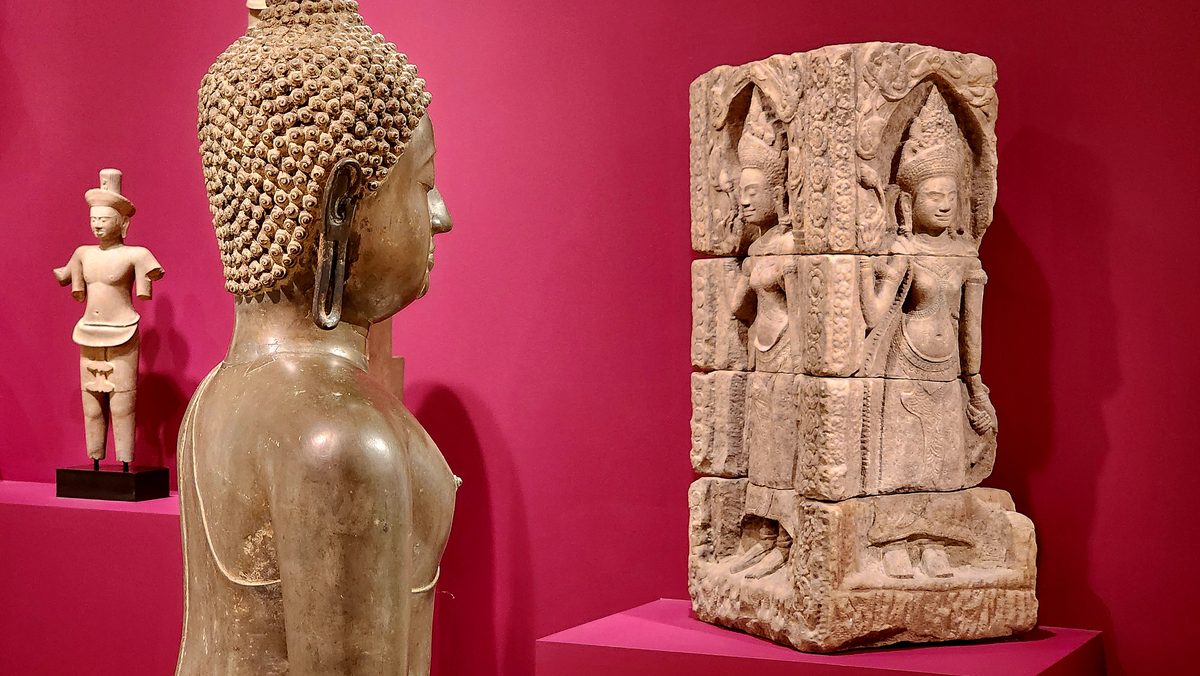 Ancient stone sculptures against a deep pink museum wall