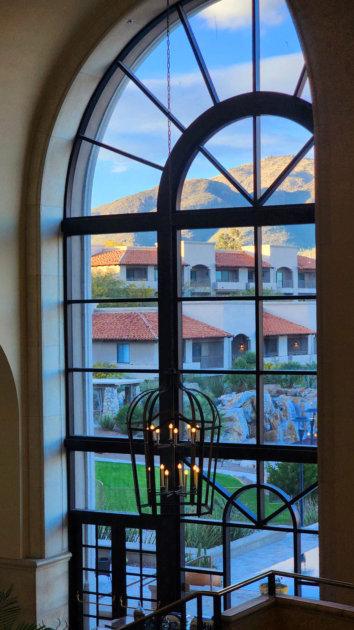 Sunset glowing through a tall arched resort window