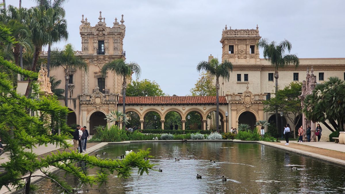 Spanish Revival building with palm trees reflected in a lily pond at Balboa Park, San Diego