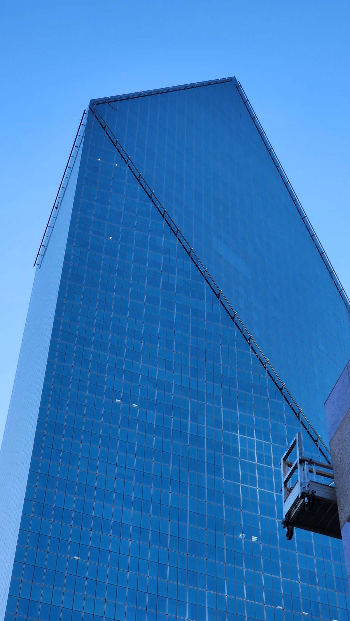 A sleek blue glass skyscraper rising into a clear sky