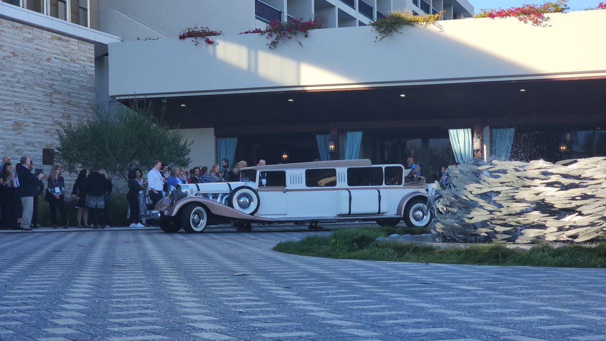 Guests gathering beside a white classic car at an outdoor event