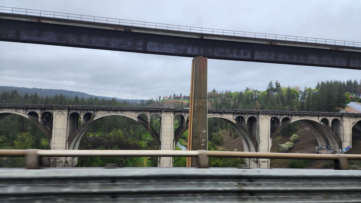 A concrete arch bridge beneath a modern highway bridge