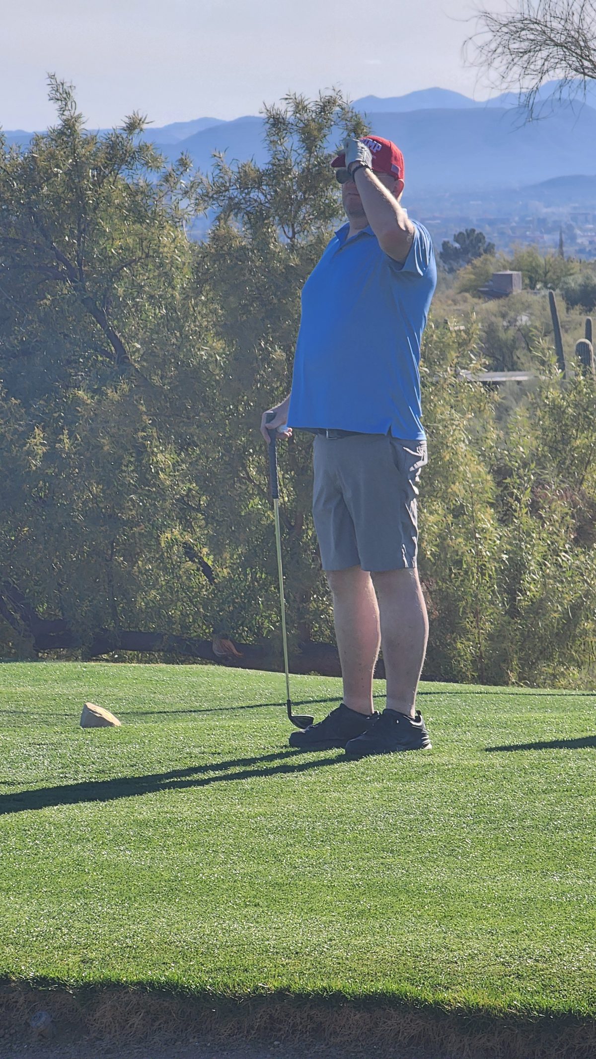A golfer on a green with desert mountains behind