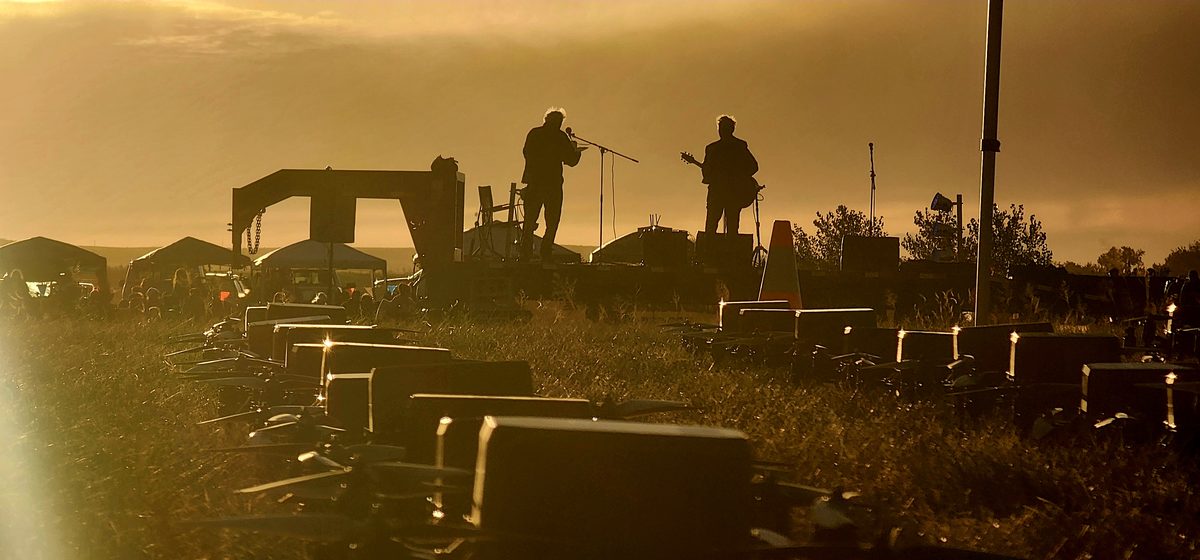Crew setting up equipment on a hazy ridge at sunset