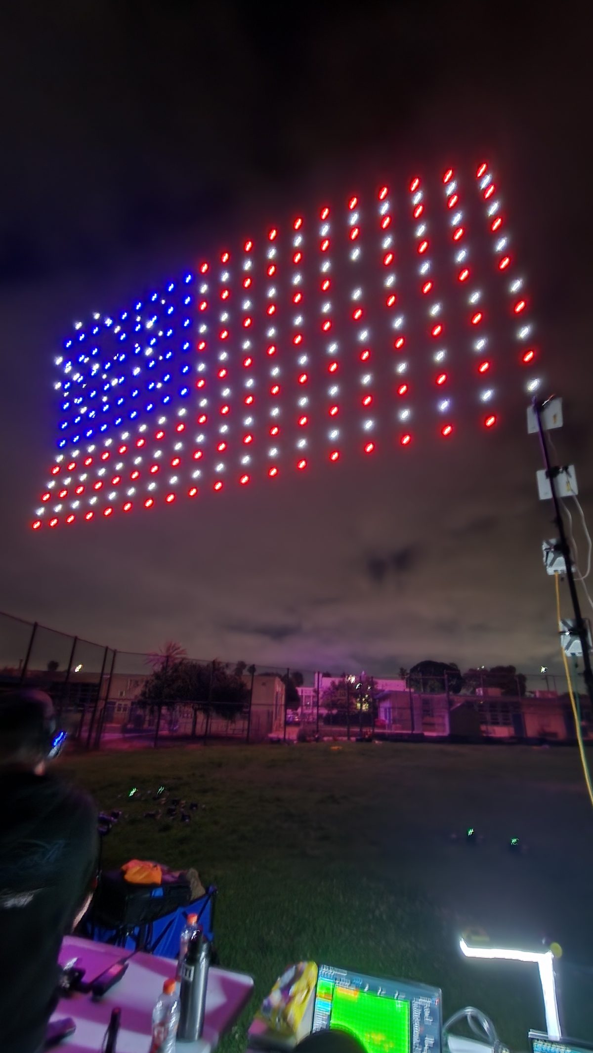 Drones forming a glowing American flag above a crowd on the Fourth of July
