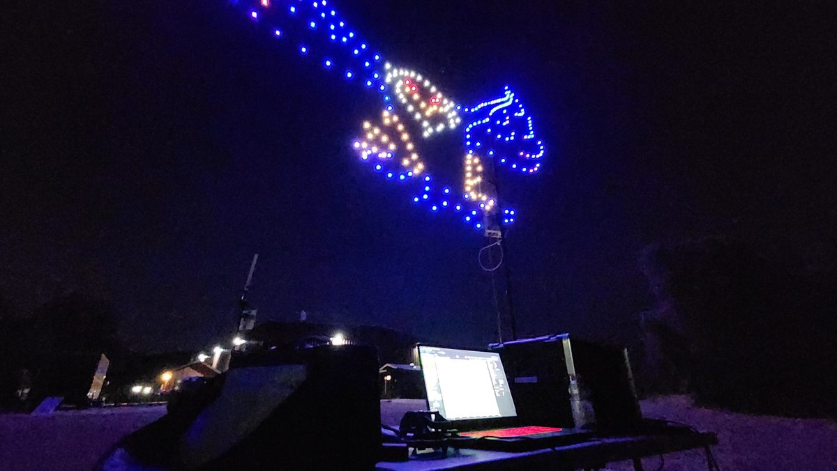 A blue and white drone formation in the sky above the pilot's control desk