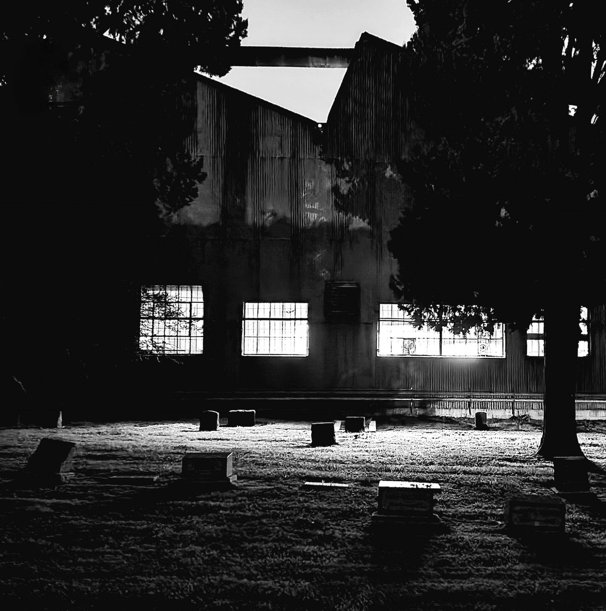 Black-and-white photo of a dim warehouse hangar with high windows at night