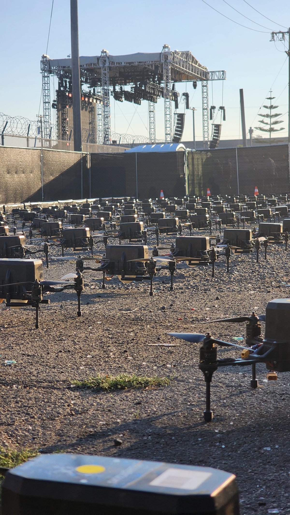 Rows of drones laid out on gravel beneath stage scaffolding