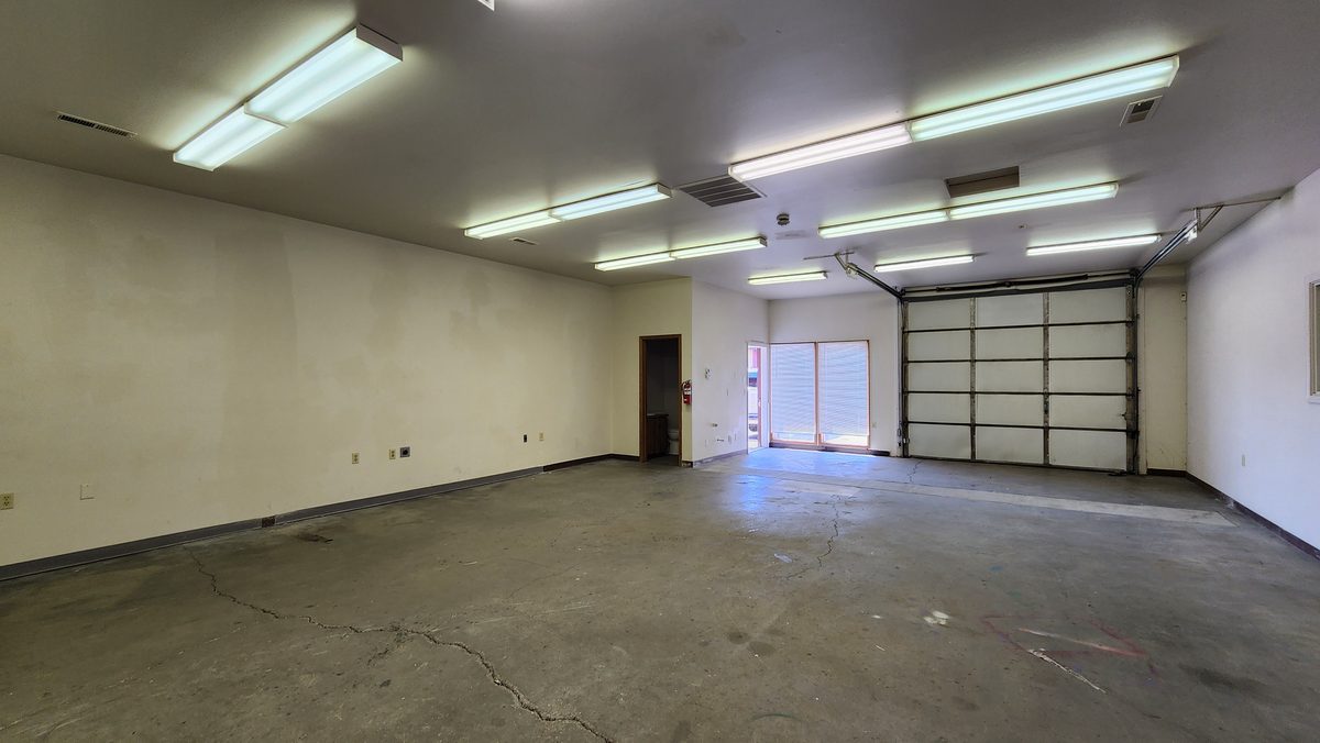 An empty white warehouse bay with roll-up doors