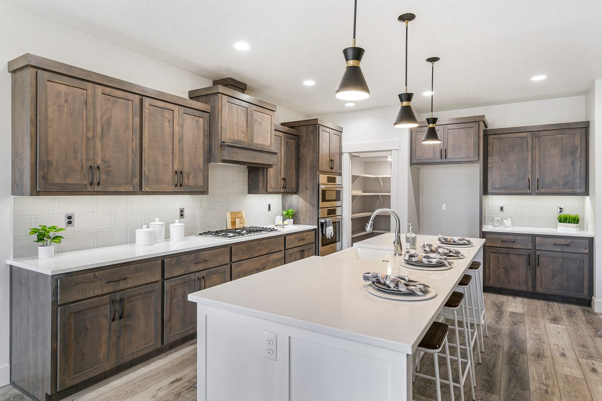 Kitchen with espresso-stained cabinets, a white quartz island with stools and pendant lights