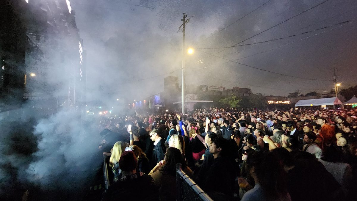 Haze and smoke drifting over a large festival crowd at night