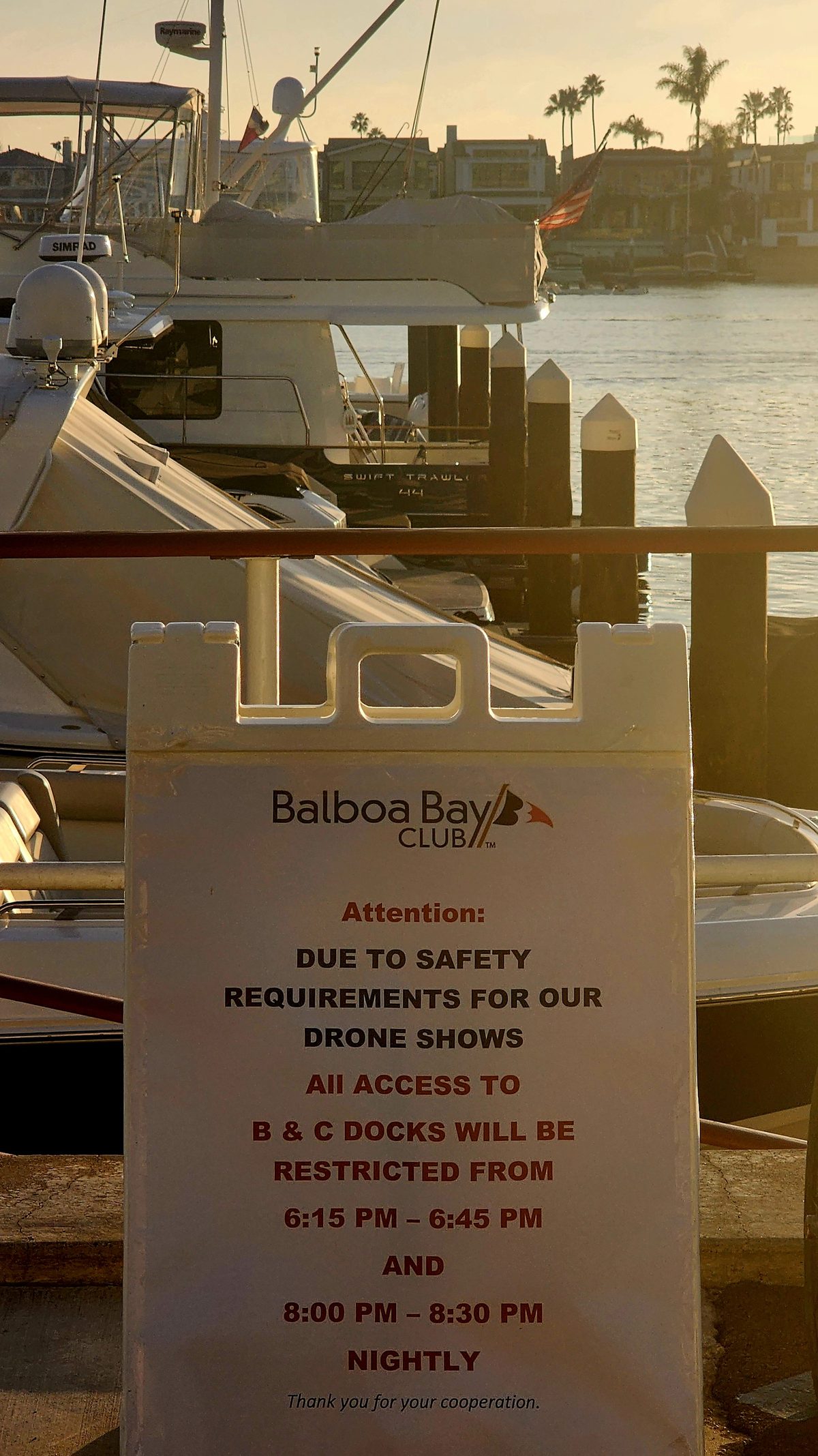 A printed notice taped by the harbor with yachts behind
