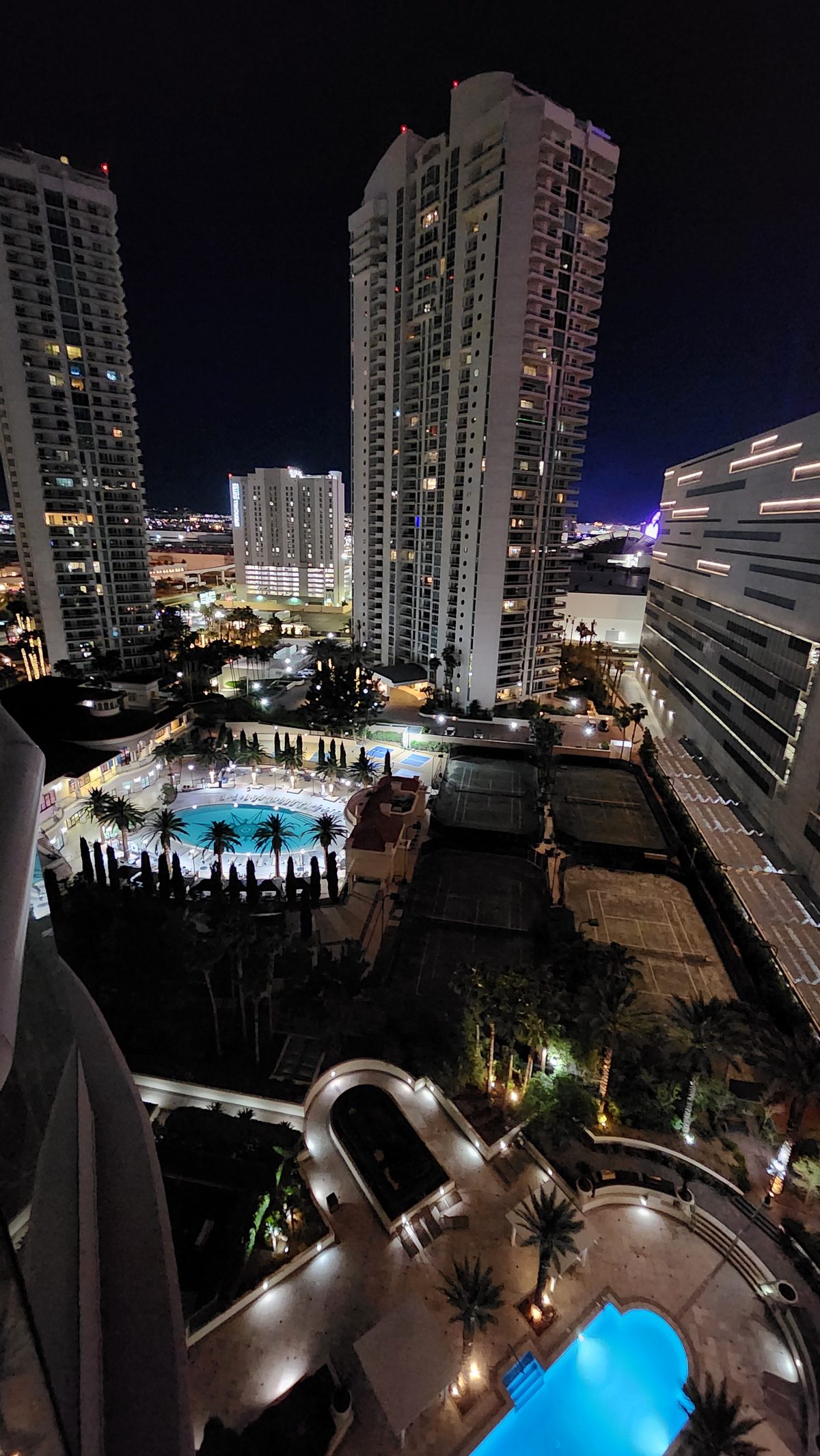 Hotel towers and a rooftop pool lit up at night