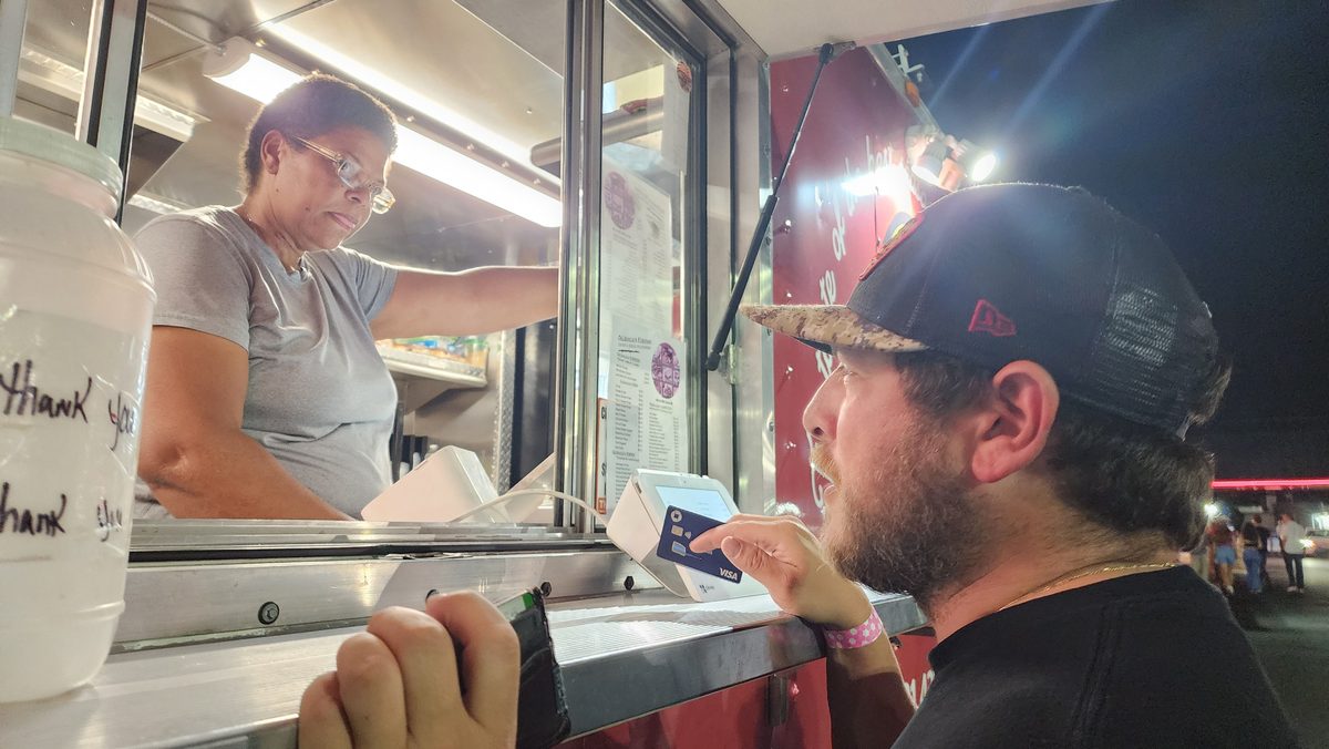 A man in a cap ordering at a late-night food window