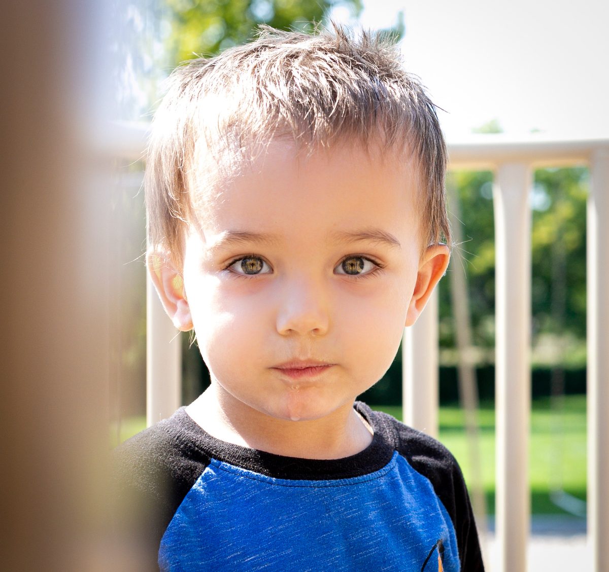 Close portrait of a young boy with big eyes peeking around a doorway