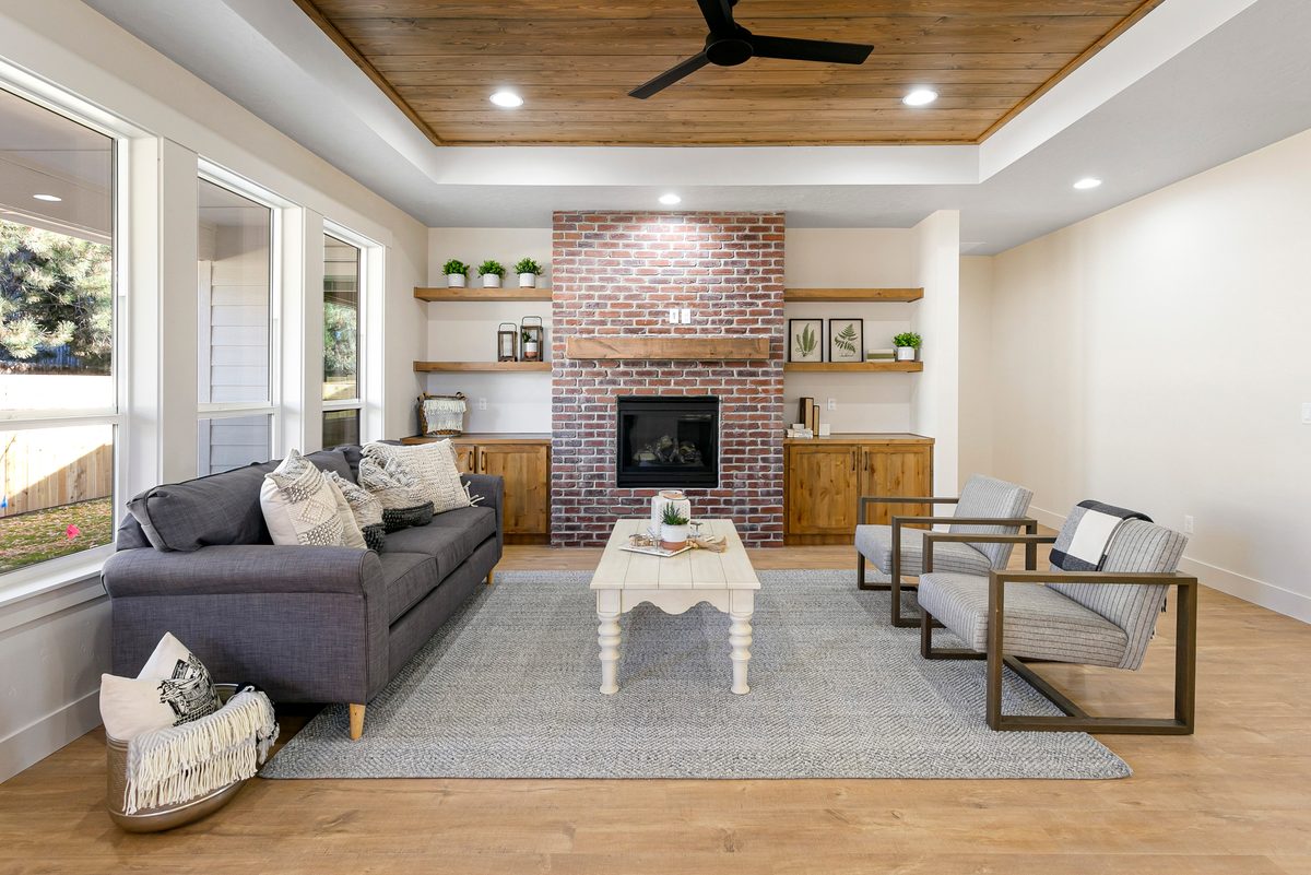 Living room with a brick fireplace, built-in shelves and a tongue-and-groove wood ceiling