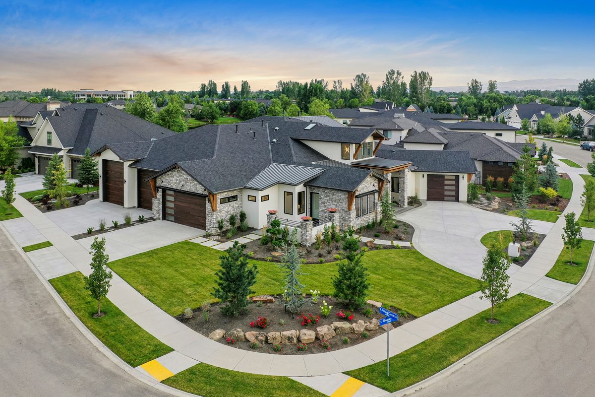 Drone photo of a luxury single-level home with landscaped entry gardens at dusk