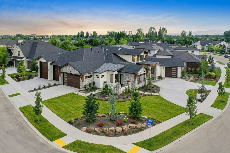 Drone photo of a luxury single-level home with landscaped entry gardens at dusk