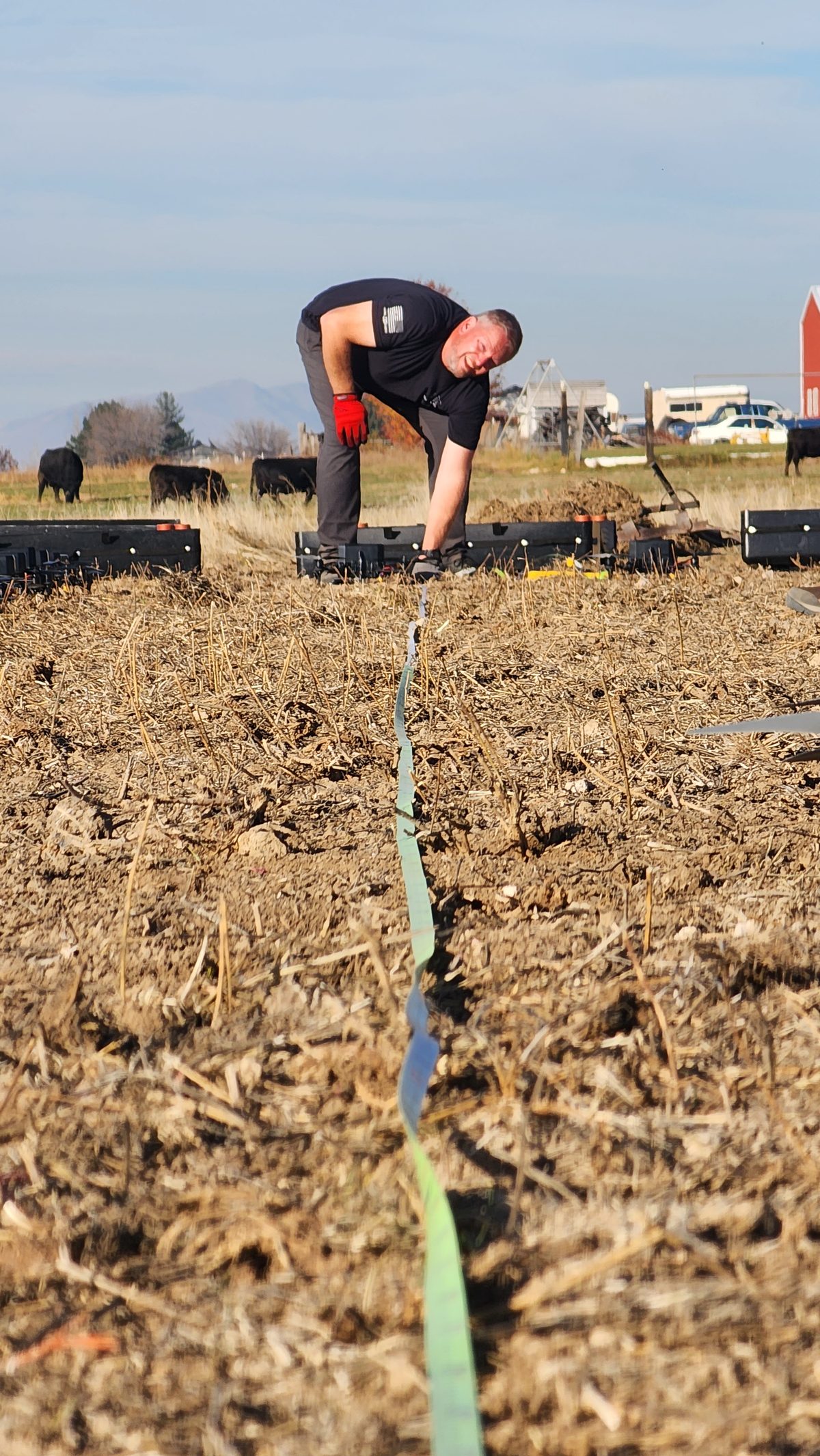 A crew member stretching a line to mark the drone launch grid on a dirt field