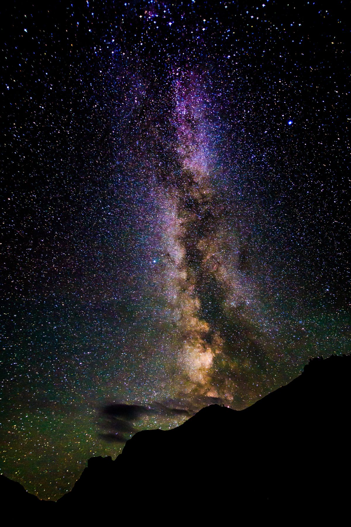 The Milky Way rising above a dark canyon ridge under a star-filled sky