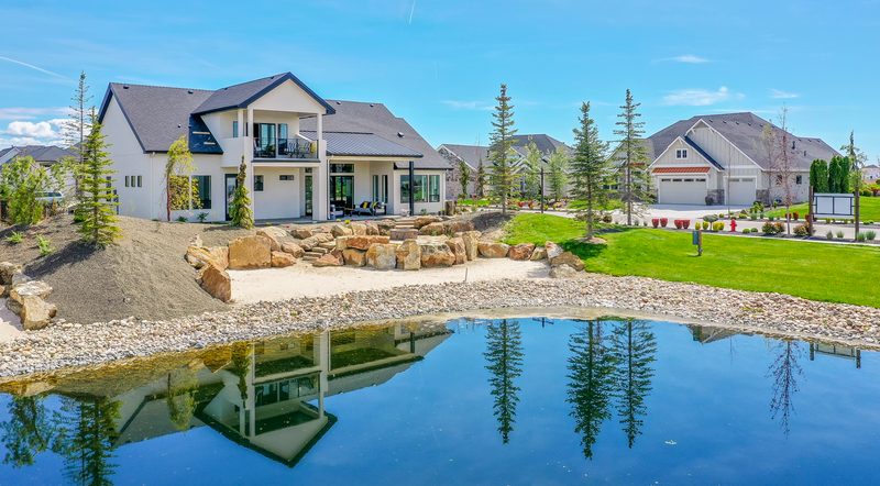Modern farmhouse homes reflected in a large backyard pond