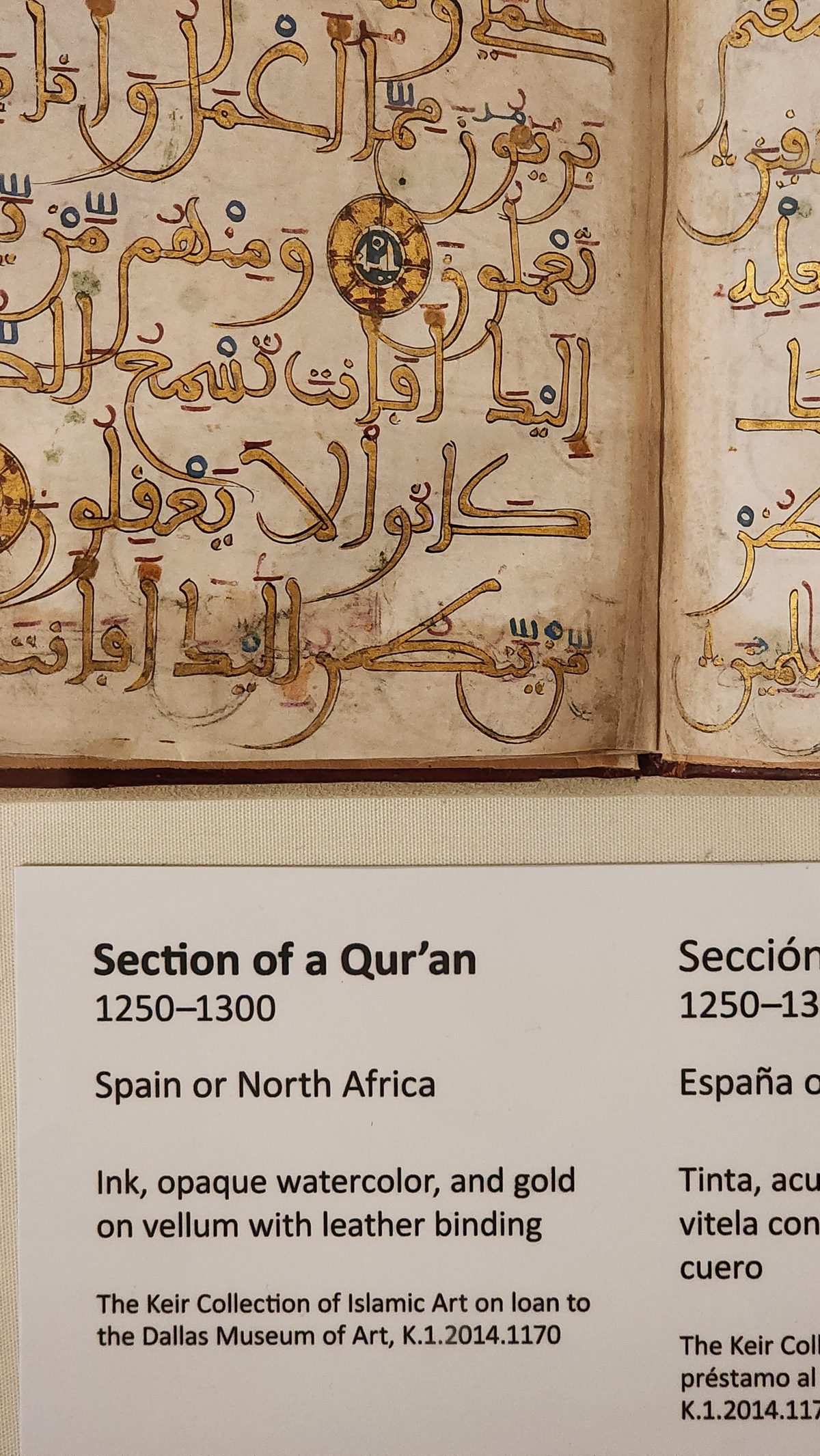 A museum display of a medieval Quran manuscript page in gold Arabic script