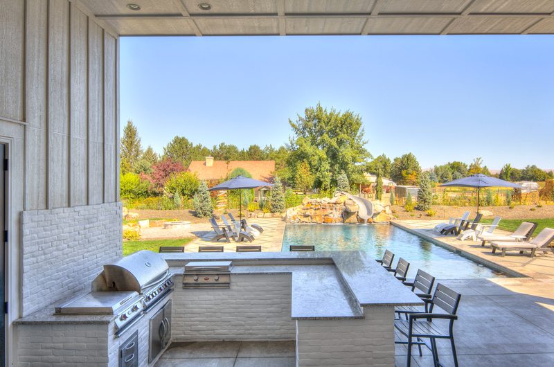Outdoor kitchen counter looking out to a pool and patio under a blue sky