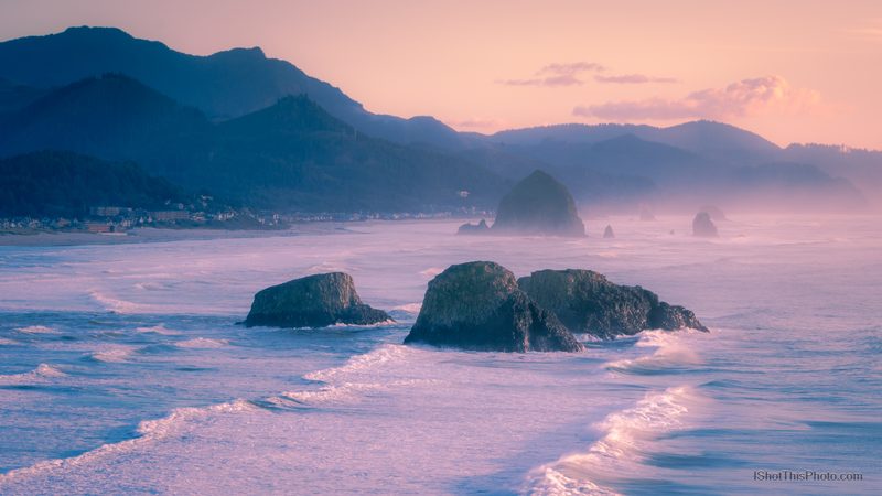 Waves washing around sea stacks under pink pastel light on a misty Pacific coast