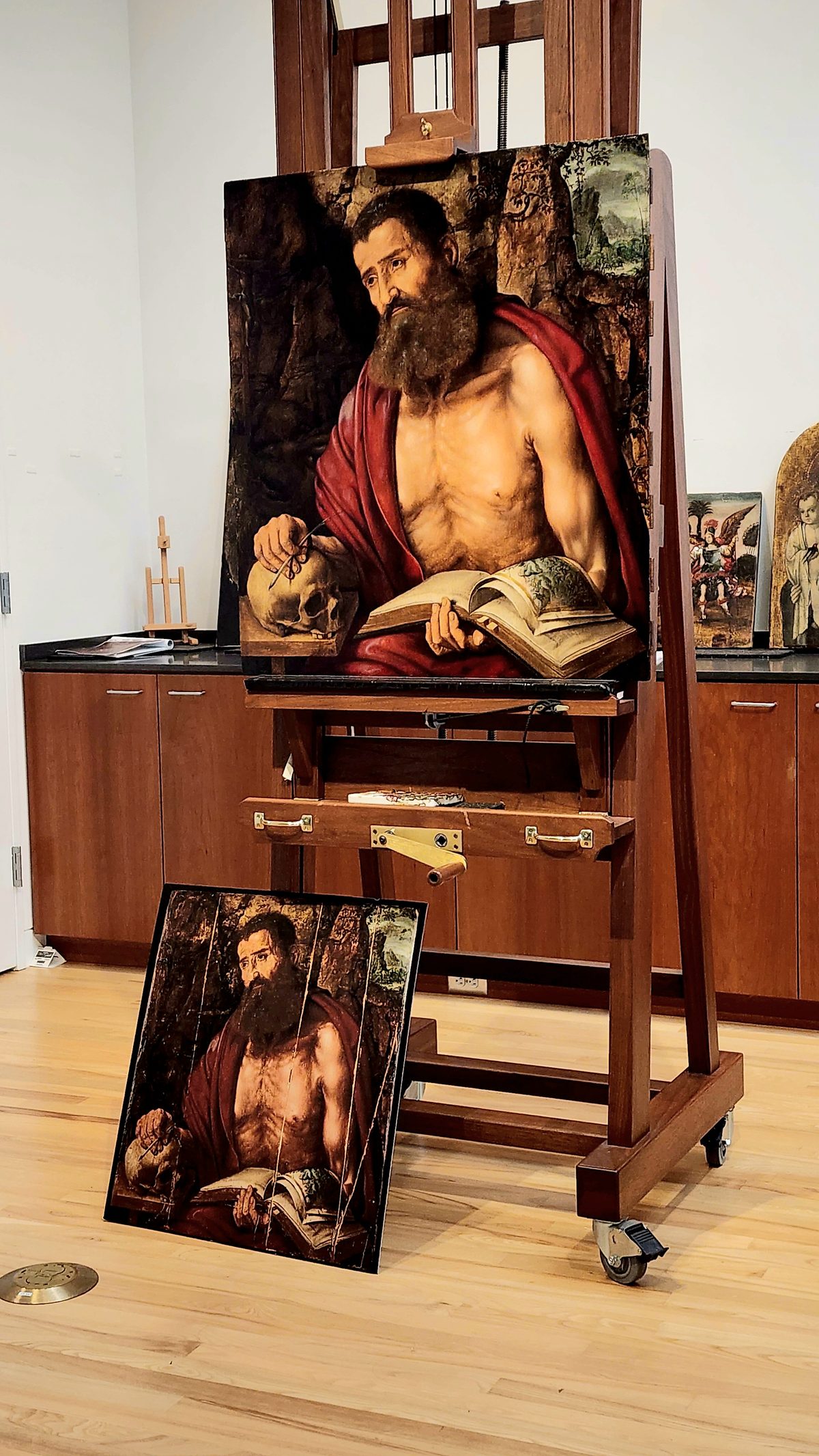 A portrait painting of a seated man displayed on a wooden easel