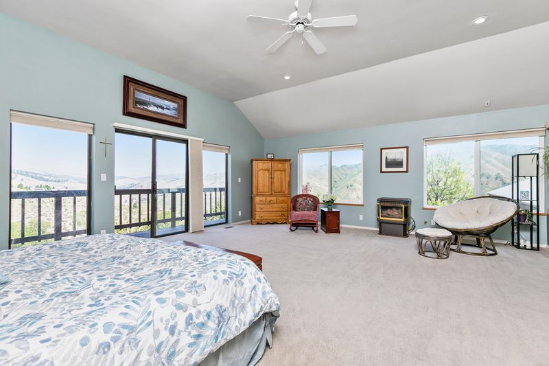 Primary bedroom with a vaulted ceiling and big windows looking out over a valley