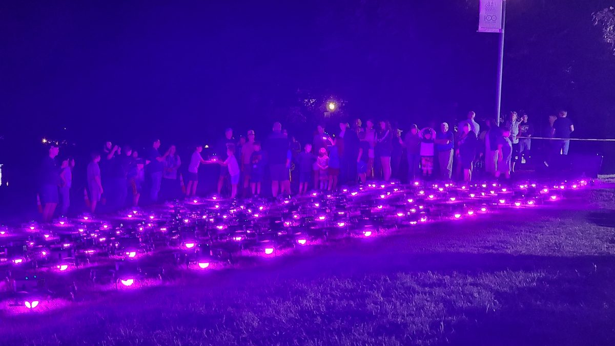 A field of drones glowing purple on the ground before launch