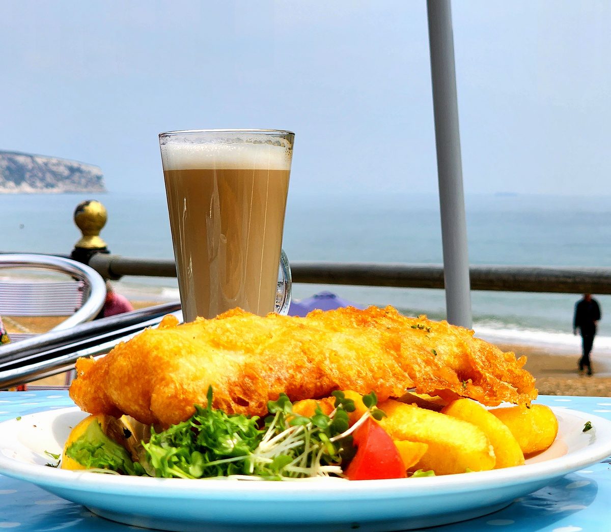 Fish and chips with a pint on a table overlooking the sea