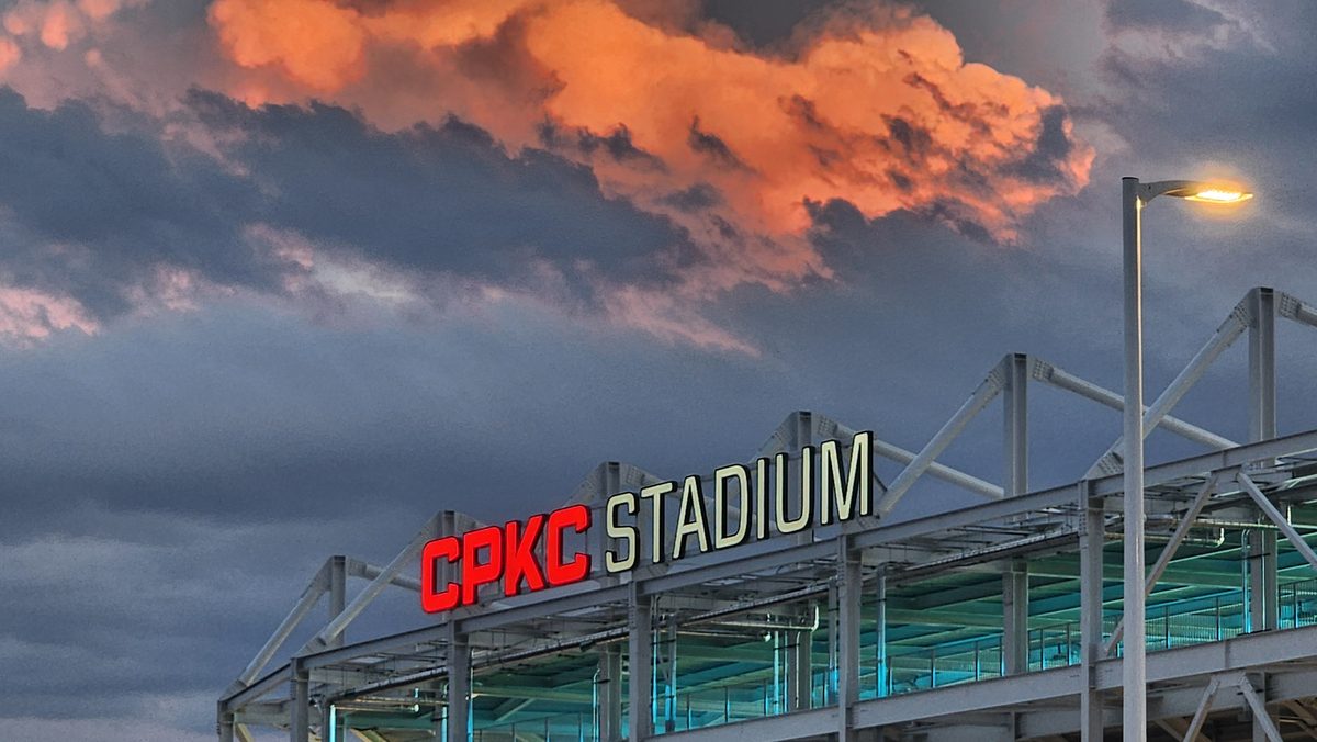 A stadium entrance under dramatic orange sunset clouds