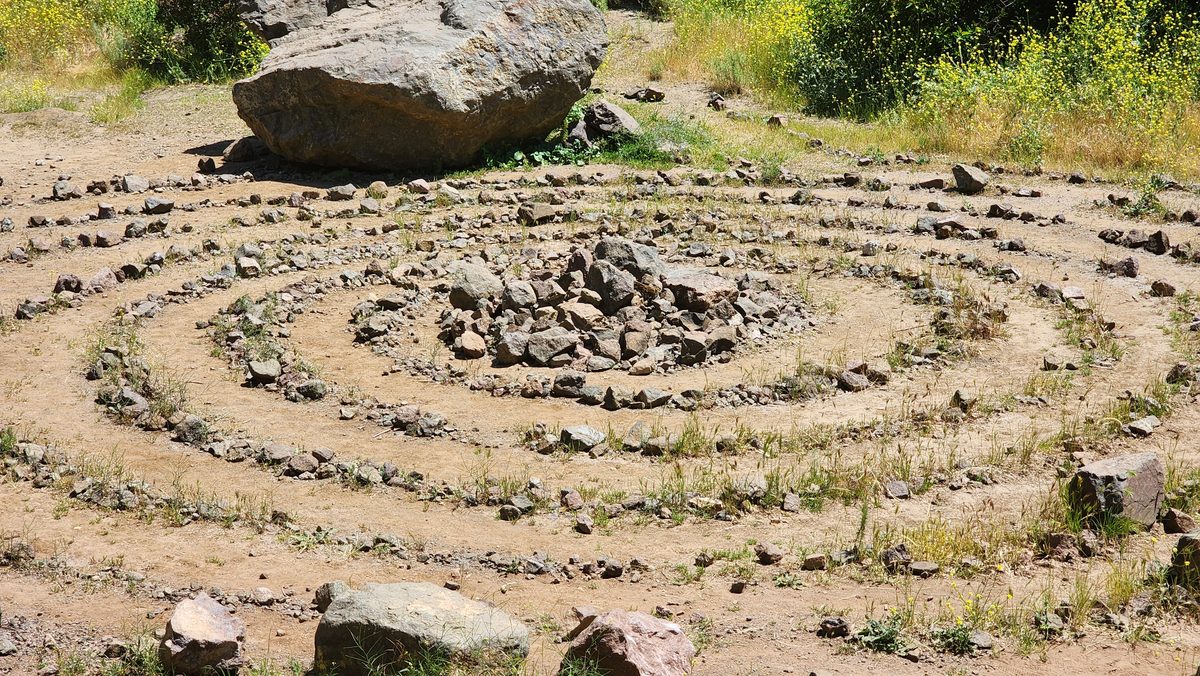 A spiral labyrinth laid out with stones on a hillside