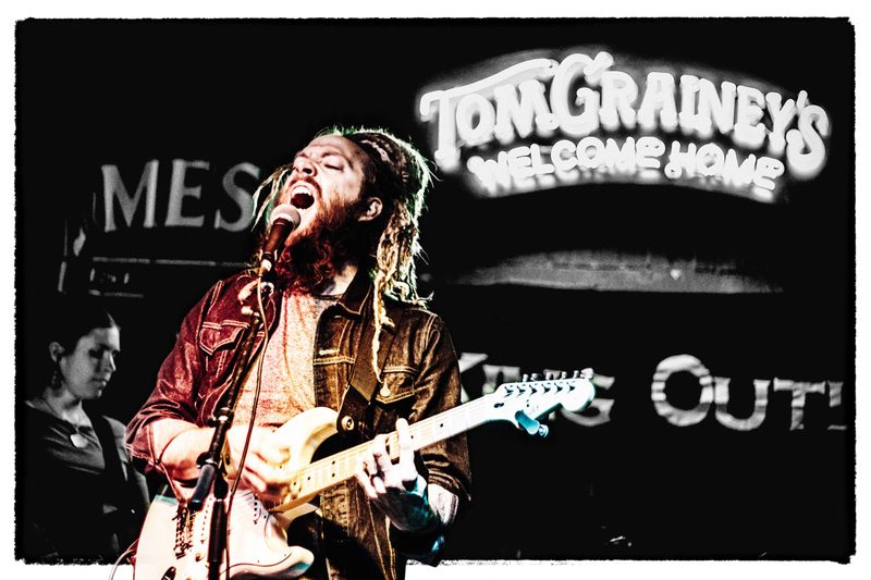A singer-guitarist belting into the mic on stage at Tom Grainey's in Boise