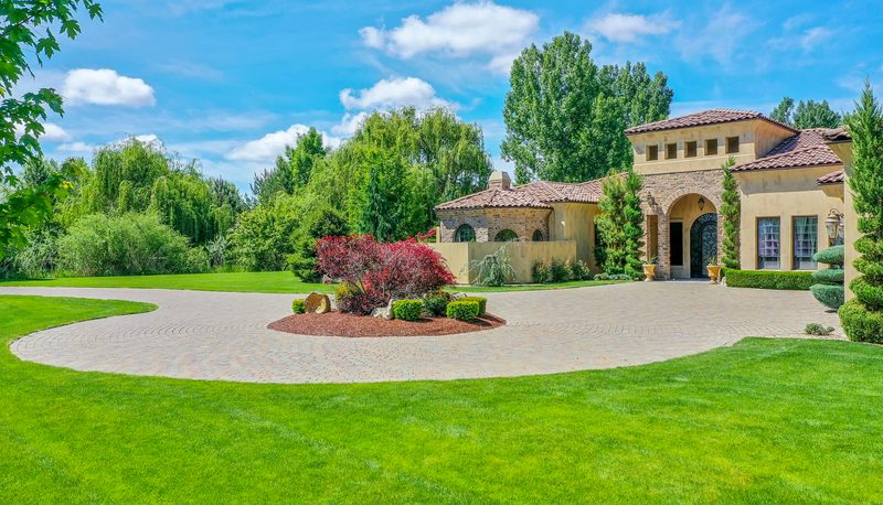 Tuscan-style stucco estate with a red tile roof, circular drive and landscaped lawn
