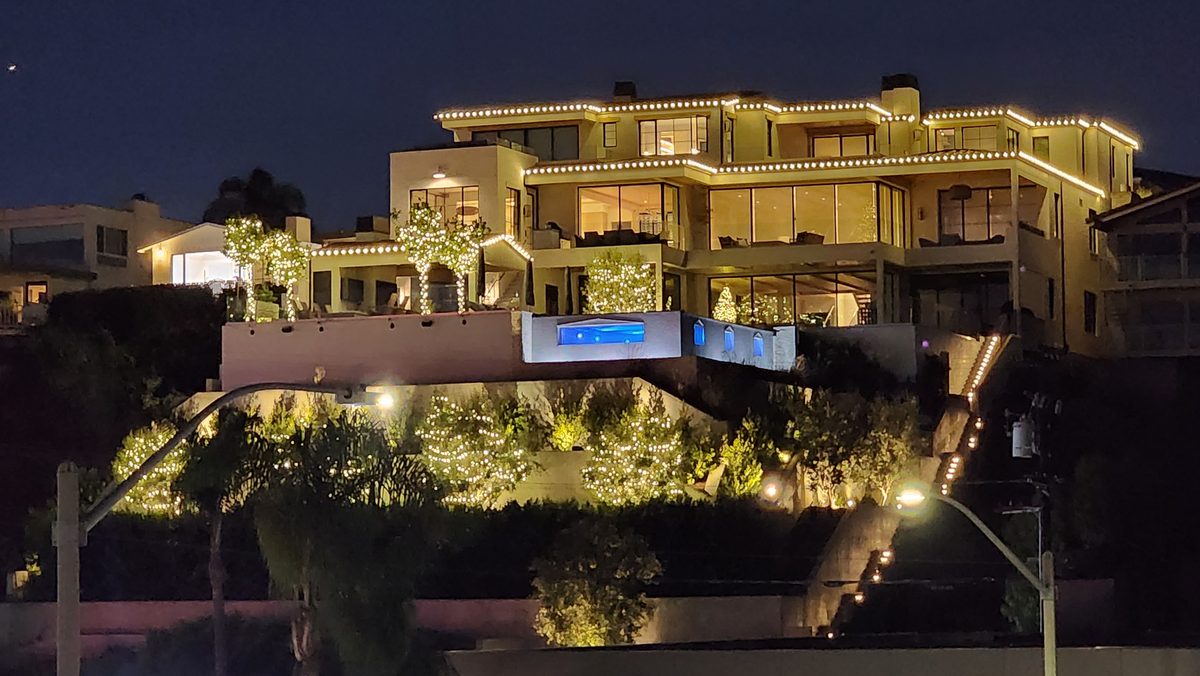 A large waterfront home lit up warmly at night