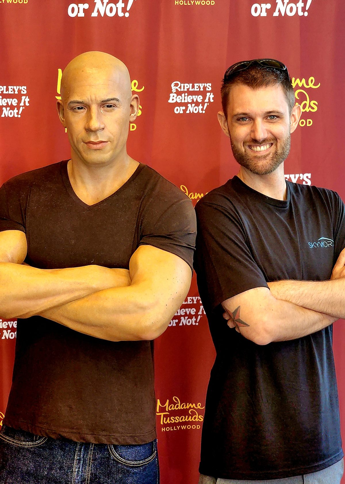 Two men posing arms crossed in front of a museum backdrop