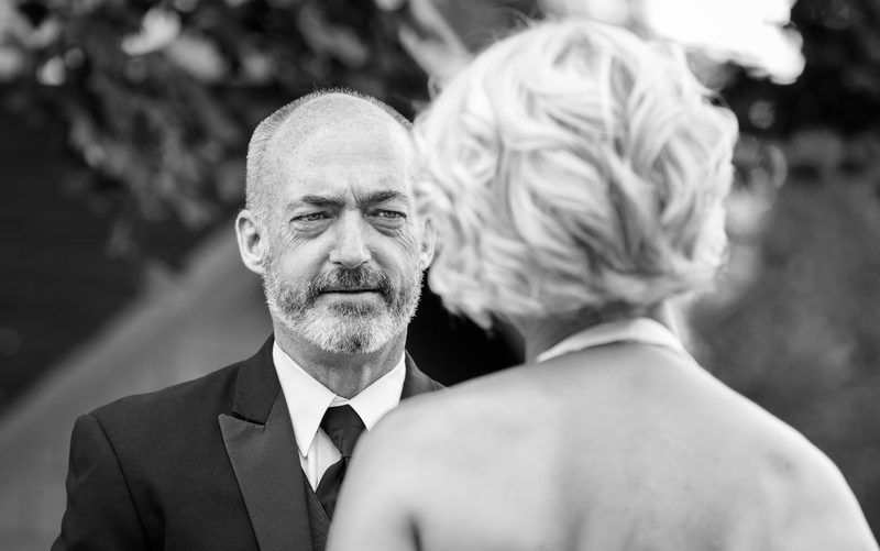 Black-and-white photo of a groom in a suit facing his bride on their wedding day