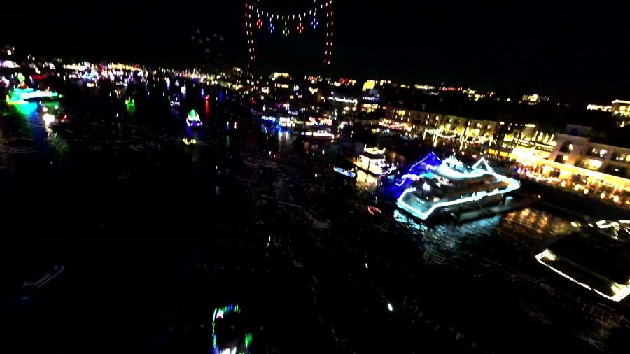 FPV flight over lit-up boats in a night-time Christmas boat parade