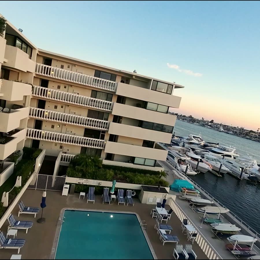 FPV drone swoops over a marina condo rooftop and pool at sunset