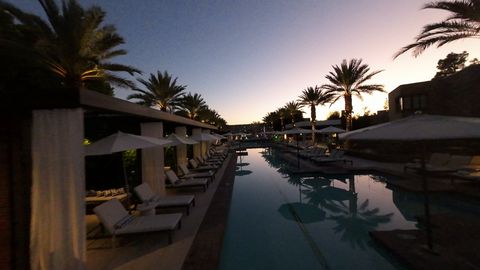 FPV flythrough over set dinner tables under umbrellas at a resort