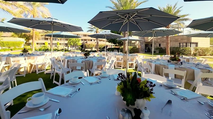 FPV flythrough over set dinner tables under umbrellas at a resort